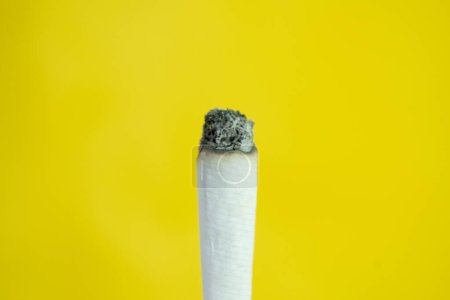 Photo for A man hand holds a handmade cigarette on yellow background - Royalty Free Image