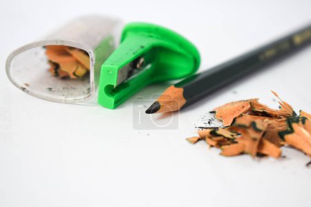 Photo for Green pencil sharpener and dark green pencils, pencil shavings on white background - Royalty Free Image