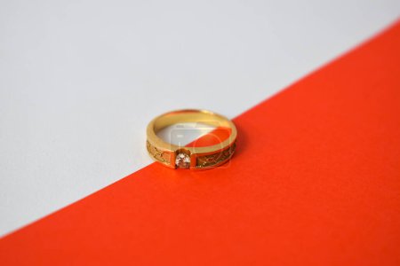 Foto de Anillo de oro con diamante en diagonal fondo blanco y naranja - Imagen libre de derechos