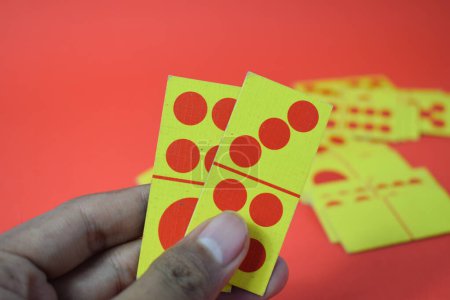 Téléchargez les photos : Main tenir dominos jouer cartes isolé rouge fond, jaune rouge dominos cartes - en image libre de droit