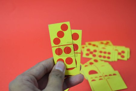 Foto de Mano mantenga dominó jugando cartas aislado fondo rojo, amarillo rojo dominó tarjetas - Imagen libre de derechos