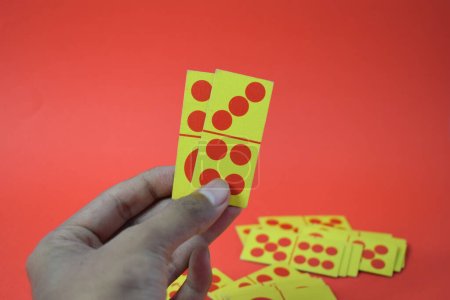 Photo for Hand hold dominoes playing cards isolated red background, yellow red dominoes cards - Royalty Free Image
