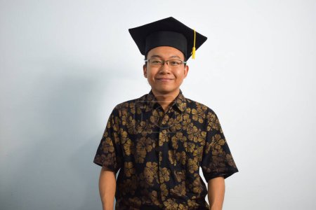 Photo for Expressive of Adult indonesia male wear batik, toga cup or graduation hat and eyeglasses isolated on white background, expressions of portrait graduation - Royalty Free Image