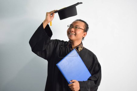Photo for Expressive of Adult indonesia male wear graduation robe, hat and eyeglasses, Asian Male graduation bring blank blue certificate isolated on white background, expressions of portrait graduation - Royalty Free Image