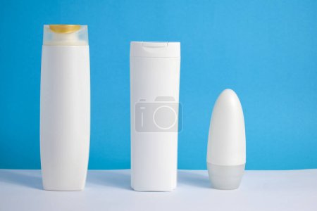Foto de Botella blanca bodycare en blanco sobre fondo azul, champú, jabón y desodorante botella, botella mockup conjunto - Imagen libre de derechos