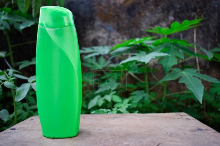 Téléchargez les photos : Produit de shampooing bouteille verte sur un fond de feuilles vertes. Produit écologique. - en image libre de droit