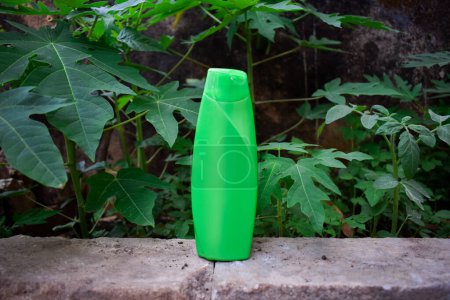Téléchargez les photos : Produit de shampooing bouteille verte sur un fond de feuilles vertes. Produit écologique. - en image libre de droit