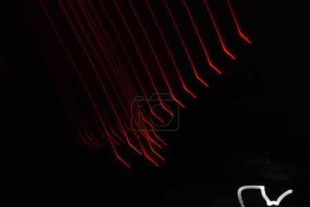 Foto de Larga exposición colorida línea abstracta pintura fondo aislado en negro. líneas curvas de iluminación de tira led sobre fondo negro - Imagen libre de derechos