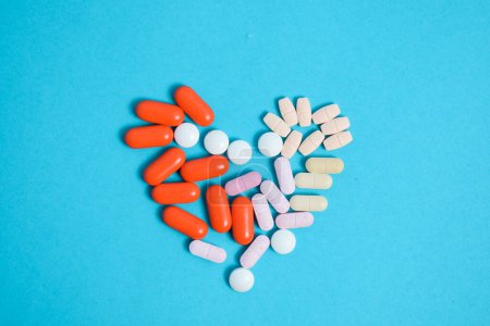 Photo for Colorful Medicine Pills in heart shape isolated on blue background, supplement, vitamin, colorful - Royalty Free Image