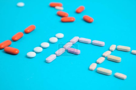 Foto de Palabra de vida de las píldoras coloridas de la medicina aisladas en fondo azul, suplemento, vitamina, colorido - Imagen libre de derechos