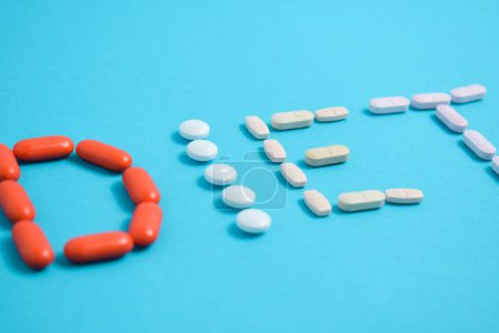Foto de Palabra de la dieta de las píldoras coloridas de la medicina aisladas sobre fondo azul, suplemento, vitamina, colorido - Imagen libre de derechos