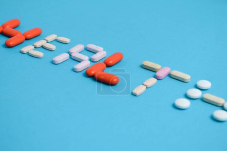 Foto de Palabra de la salud de las píldoras coloridas de la medicina aisladas en fondo azul, suplemento, vitamina, colorido - Imagen libre de derechos