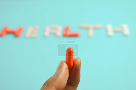 Téléchargez les photos : Homme main tenir pilule rouge, mot de santé de fond de pilules de médecine colorée, supplément, vitamine, coloré - en image libre de droit