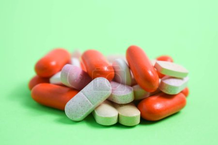 Photo for White spoon with colorful medical pills on green background, copy space - Royalty Free Image