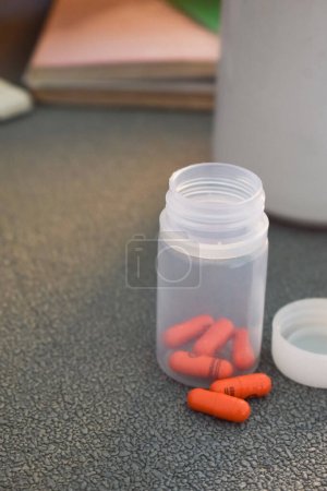 Foto de Cápsula píldora médica y botella con taza o vidrio de agua en el espacio de trabajo de la mesa - Imagen libre de derechos