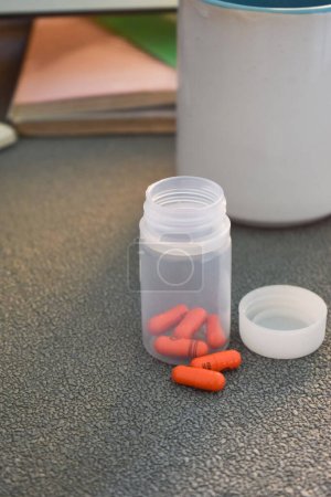 Téléchargez les photos : Capsule de pilule médicale et bouteille avec tasse ou verre d'eau sur l'espace de travail de table - en image libre de droit