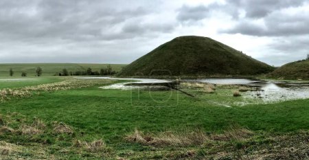 Téléchargez les photos : Silbury Hill, Avebury, Wiltshire. Le plus haut monticule artificiel préhistorique d'Europe, vieux d'environ 4600 ans. Février 2020. Sous le ciel gris. - en image libre de droit