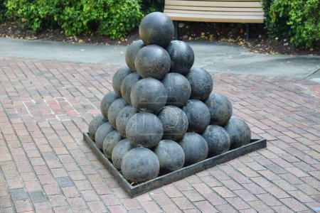 Photo for Pile of Black Cannon balls on brick flooring with bench behind. Fort Monroe, Hampton VA. USA. Vintage ammunition. - Royalty Free Image