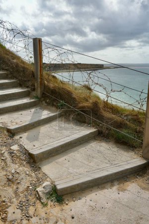 Photo for Wood and concrete steps with barbed wire behind, sea and cliffs in the background. Pointe du Hoc, France. - Royalty Free Image