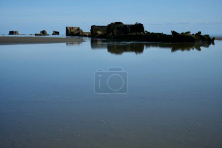 Photo for Remains of the WW2 D-Day Mulberry Harbour at Asnelles Beach reflected in a glassy sea. Arromanches, France, July 5, 2023. - Royalty Free Image