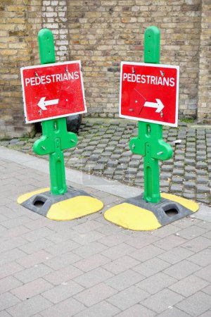 Foto de Signos de flecha peatonal de color rojo y verde en soportes amarillos y negros. Woolwich, Londres, Reino Unido, 16 de marzo de 2024. - Imagen libre de derechos