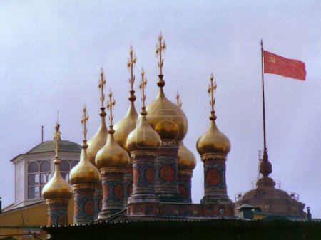 Téléchargez les photos : Image de l'ère soviétique de dômes d'oignon d'or au-dessus de la cathédrale du Sauveur supérieur au Kremlin avec drapeau rouge de l'URSS flottant. Moscou, Russie, le 1er septembre 1989. - en image libre de droit