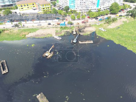Téléchargez les photos : Dragage du lac au milieu de la ville qui a beaucoup de boue en elle et l'eau est devenue noire - en image libre de droit