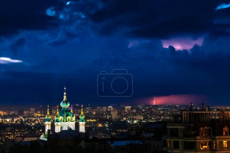 Photo for Saint Andrews Church in Kiev, Ukraine, seen in blue hour twilight with a thunderstorm and lightning in the background. Approaching dark storm seen on the horizon. - Royalty Free Image