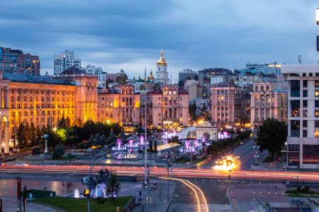 Foto de La plaza europea en Kiev, Ucrania antes de la guerra, Majdan Nezalezjnosti. Foto de alta calidad con luz que se desvanece en la noche de hora azul. Las luces de la calle y los coches son visibles, la luz ilumina las estatuas - Imagen libre de derechos