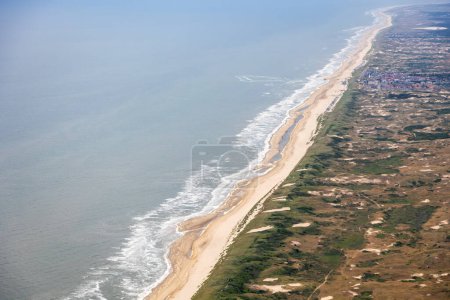 Photo for Aerial image of the Dutch coastline with breaking waves on the golden beach and sand dunes protecting The Netherlands . High quality photo - Royalty Free Image