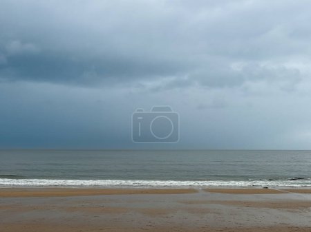 Foto de Nubes de lluvia oscura sobre el oleaje en la playa con arena dorada y olas en Whitley Bay, Newcastle, Inglaterra. Foto de alta calidad - Imagen libre de derechos