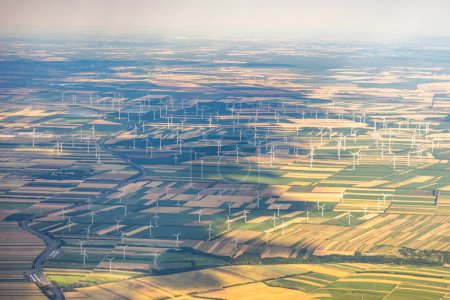 Photo for Many windmills or wind turbines for green, renewable, energy or electricity on a hilltop between colourful fields in Austria, near Vienna in warm glow of afternoon sunlight. High quality photo - Royalty Free Image