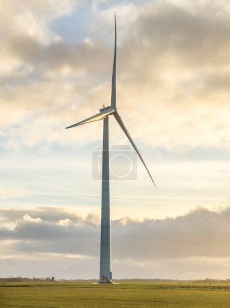 Foto de Alto molino de viento de energía verde único o turbina en la granja, en el campo de pastizales bajo el amanecer. Foto de alta calidad - Imagen libre de derechos