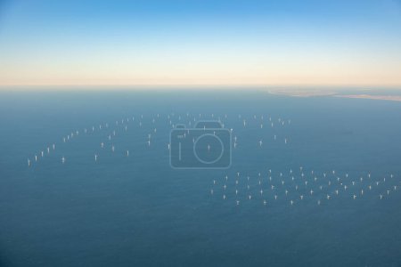 Aerial image of large off shore wind farm with turbines at sea before Dutch coast, shore of Holland in the distance . High quality photo