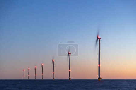 Off shore wind turbines or wind mills at sea at blue dusk, long exposure and stars visible. High quality photo