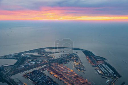 Luftaufnahme des Hafenterminals von Rotterdam mit vielen Docks, Schiffen und Kais im künstlich angelegten Hafen ins Meer, Ozean bei hellem, farbenfrohen Sonnenuntergang. Hochwertiges Foto