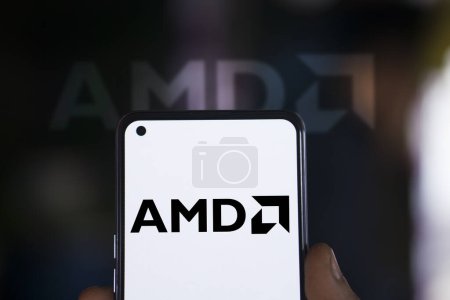 Foto de Dhaka, Bangladesh - 30 de diciembre de 2023: Mano sosteniendo un teléfono con el logotipo de AMD. Advanced Micro Devices, Inc. es una empresa multinacional estadounidense de semiconductores. - Imagen libre de derechos