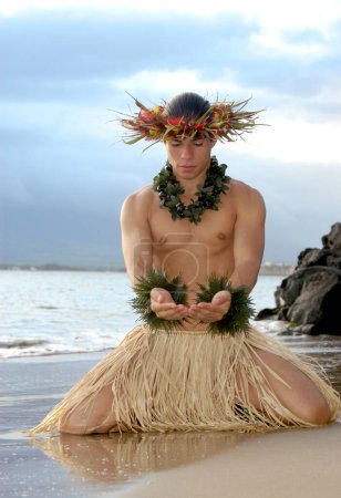 Un jeune danseur de hula masculin fait un geste d'offrande ou l'acte de donner dans une danse de hula.                                