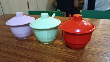 Téléchargez les photos : Trois petits pots d'épices en orange, turquoise et violet sur une table à manger - en image libre de droit