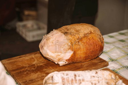 Half of a Cured Ham Ready for Slicing on Wooden Board