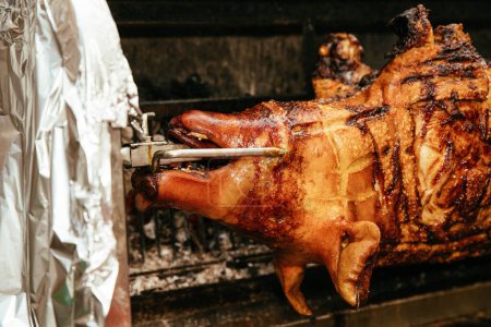 Whole pig with crispy skin roasting on a spit