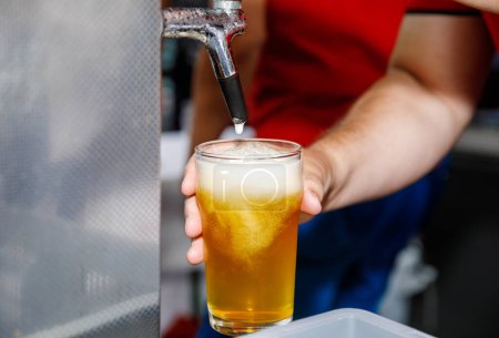Beer being poured from a tap into a glass with foam