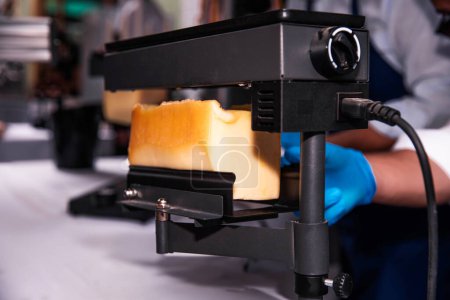 Raclettekäse mit einem elektrischen Schmelzgerät schmelzen und in Scheiben schneiden