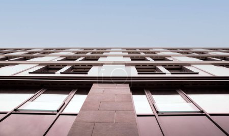 Aufwärts gerichtete Ansicht eines Gebäudes mit geometrischen Fenstermustern und dem Kontrast seiner strukturierten Fassade