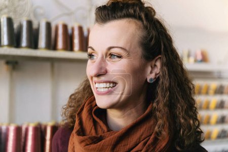 Fröhliche Frau mit lockigem Haar, die in einem Handwerksladen strahlend lächelt