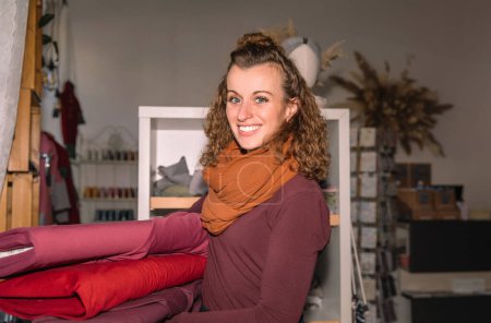 Mujer abrazando rollos de tela en su tienda creativa