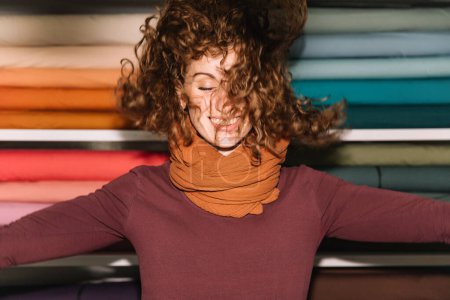 Exuberant Woman with Curly Hair Enjoying Time in a Colorful Textile Shop