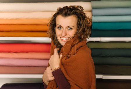 Cozy portrait of a woman with curly hair wrapped in a soft scarf, offline shopping concept