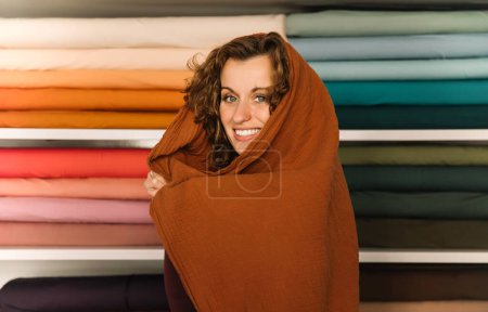 Eine charmante Frau umhüllt von Wärme und Kreativität in einem Textilladen, kreatives Gestaltungskonzept