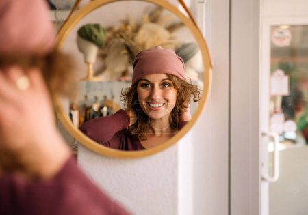 Glückliche Frau lächelt im Spiegel des Studiospiegels